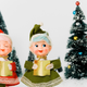 Vintage caroling figurines beside a Christmas tree